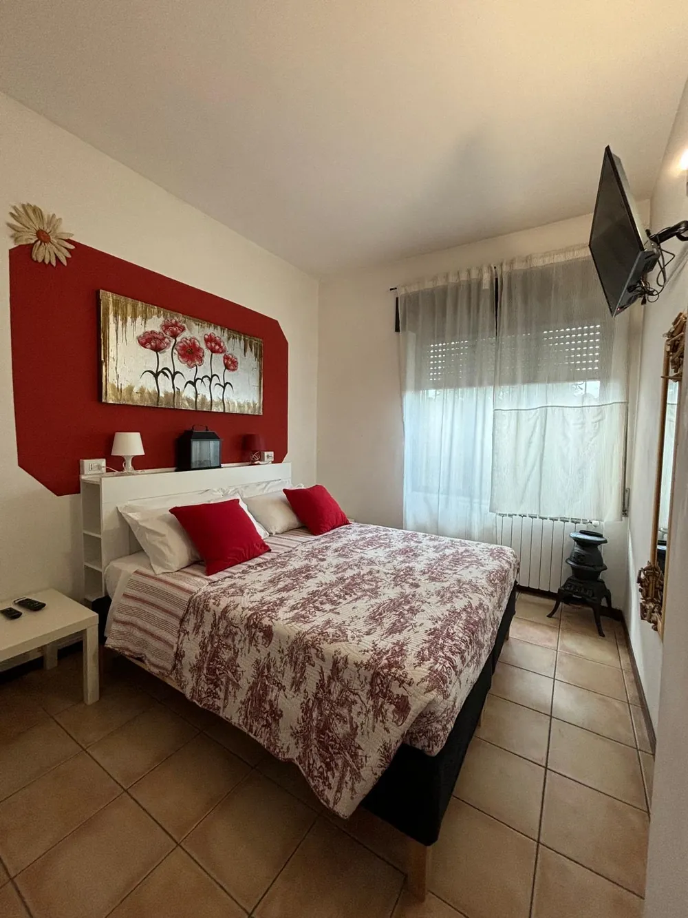 La camera da letto con parete rossa, letto matrimoniale e tessuti a motivi rossi