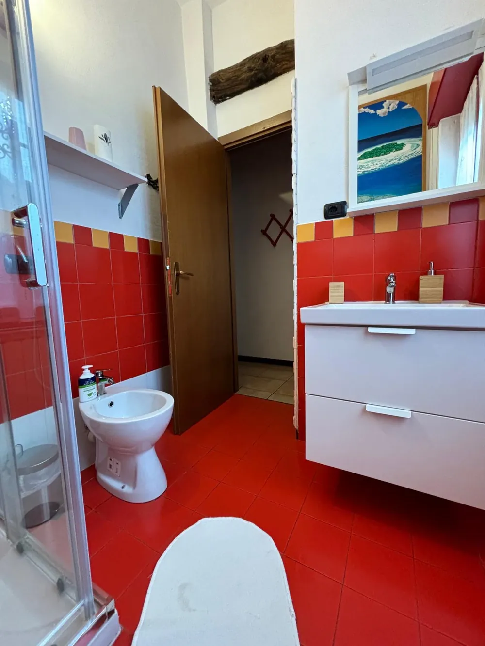 Il bagno con piastrelle rosse, doccia, bidet e mobile lavabo bianco