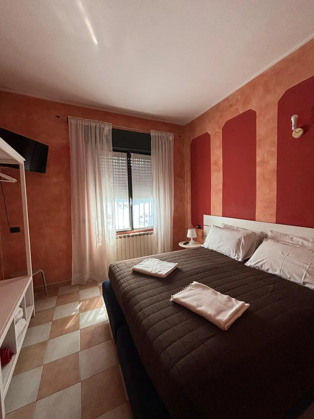 La camera da letto con pareti color terracotta, letto matrimoniale e asciugamani piegati